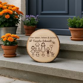 Personalisierte Familien-Baumscheibe auf einer Steintreppe vor der Haustür, umgeben von Topfpflanzen mit orangefarbenen Blüten.