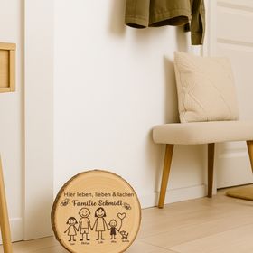 Personalisierte Familien-Baumscheibe auf einer Steintreppe vor der Haustür, umgeben von Topfpflanzen mit orangefarbenen Blüten.