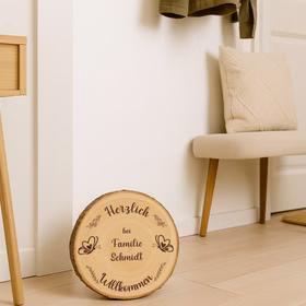 Personalisierte Baumscheibe als Holzschild im modernen Flur neben Pflanze und Holzbank, Durchmesser ca. 30 cm.