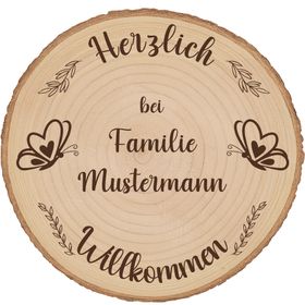 Personalisierte Baumscheibe als Willkommensschild im sommerlichen Blumenbeet vor einem Hauseingang, mit Gravur und Schmetterlingsmotiv.