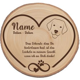 Personalisierte Baumscheibe mit Hundemotiv als Gedenkstelle zwischen roten Rosen im Garten.