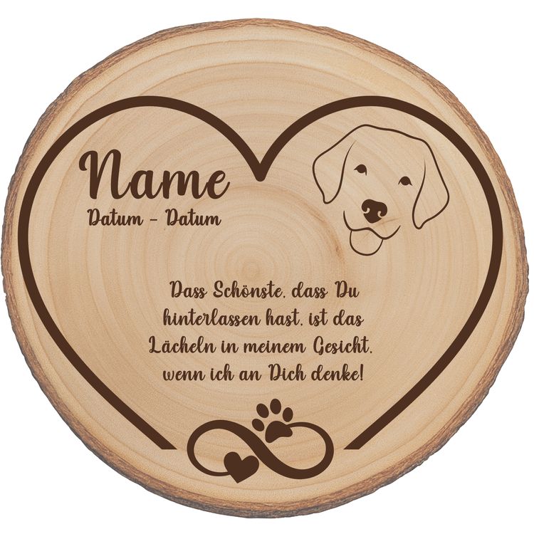 Personalisierte Baumscheibe mit Hundemotiv als Gedenkstelle zwischen roten Rosen im Garten.