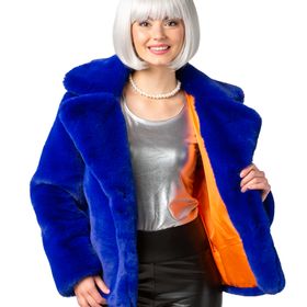 Dame trägt royalblaue Plüschjacke im 90er-Retro-Look mit passendem Plüschhut, schwarze Hose und silberne Pumps vor weißem Hintergrund.