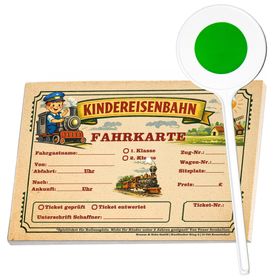 Ein lächelnder Junge im dunkelblauen Schaffnerkostüm mit roter Mütze hält in der linken Hand eine grüne Signalkelle und in der rechten Hand eine Spiel-Fahrkarte der Kindereisenbahn.