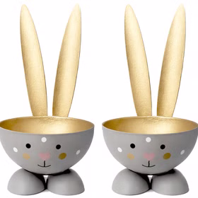 Zwei graue Hasen-Eierbecher mit goldenen Ohren auf weißem Hintergrund, nebeneinander positioniert; beide zeigen ein gemaltes Gesicht mit rosa Herz-Nase.