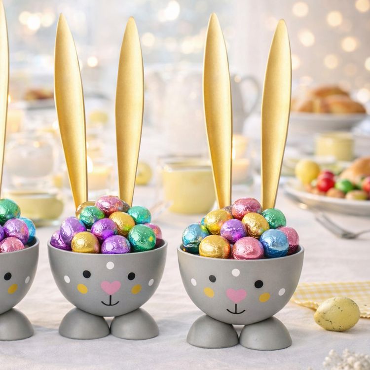 2 Eierbecher Hase Grau aus Metall Osterhase 10 cm gedeckter Tisch Ostern Zwei graue Hasen-Eierbecher mit goldenen Ohren auf weißem Hintergrund, nebeneinander positioniert; beide zeigen ein gemaltes Gesicht mit rosa Herz-Nase.