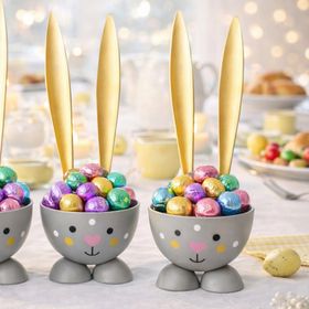 Vier graue Hasen-Eierbecher mit goldenen Ohren auf weißem Hintergrund; unten rechts befindet sich ein runder Hinweis mit der Aufschrift „4 Stück“.