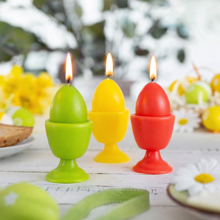 Osterkerzen 3er-Set bunt im Eierbecher Tischdeko Ostern Drei bunte Kerzen in Eierform mit integriertem Eierbecher-Design in Rot, Grün und Gelb vor weißem Hintergrund.