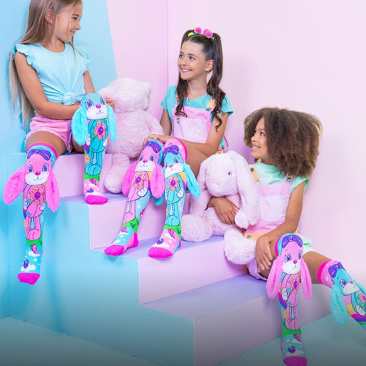 Kind trägt bunte Kniestrümpfe mit großem Hasenmotiv in Pink und Türkis. Die Socken haben flauschige 3D-Ohren und zeigen Blumen-, Vogel- und Wolkenmotive.