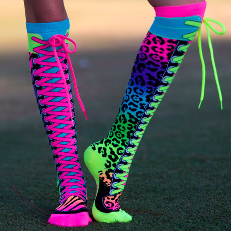 Lustige Socken Neon-Safari Bunt 80 & 90er Style Bunt für Kinder & Erwachsene Fun-Socken Spaßsocken 80er Jahre 90er Jahre Neon-Party Kostüm-Zubehör Fasching Karneval Mottoparty Festival Neon-Safari Socken mit pinken und grünen Schnürsenkeln, getragen auf einer Rasenfläche im Freien.