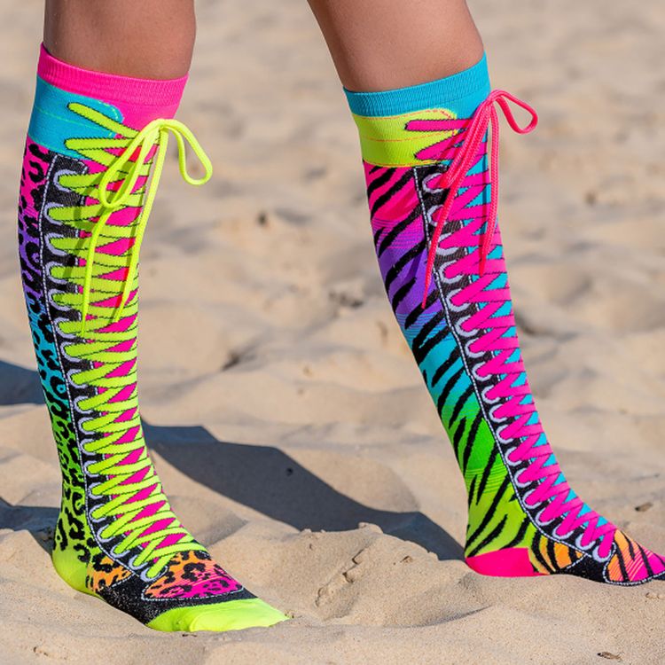 Knallbunte Neon-Kniestrümpfe im Safari-Design mit Zebra- und Leopardenmuster sowie aufgenähten Schnürsenkeln in Pink und Neon-Grün, seitlich am Bein getragen.
