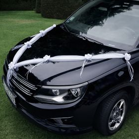 Detailansicht der weißen Hochzeitsgirlande mit Rosenblüten entlang der Motorhaube eines Fahrzeugs.