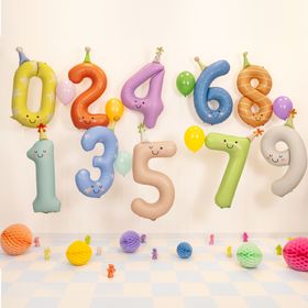 Farbenfrohe Geburtstagsdekoration mit schwebenden Zahlenballons von 0 bis 9 in Pastellfarben, ergänzt durch Luftballons und Papierdekoration auf einem festlich dekorierten Boden.