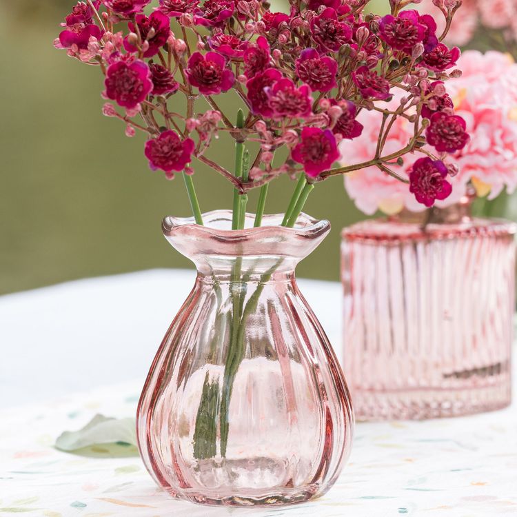 Zwei rosafarbene Glasvasen im Set – große Blumenvase und kleine Mini-Vase mit gewelltem Rand vor neutralem Hintergrund.