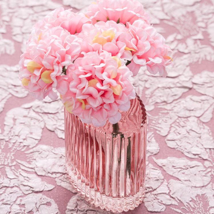 Mini Glasvase „Helios“ 8 cm hoch Tisch-Deko Vase Vintage Tisch-Deko Hochzeit Geburtstag Vase aus Glas festliche Tischdeko Wohnaccessoire Glasvase dekorativ Rosa Mini-Glasvase „Helios“ mit rosafarbenen Kunstblüten auf gemustertem Untergrund als dekorative Vintage-Tischdeko.