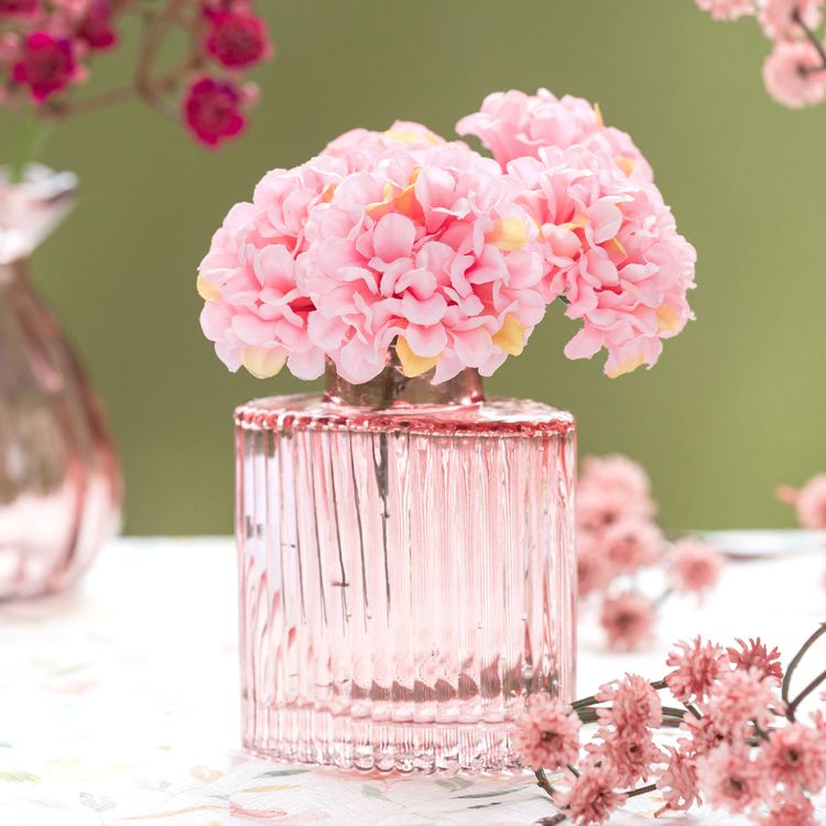 Drei rosa Glasvasen in unterschiedlichen Größen vor weißem Hintergrund.