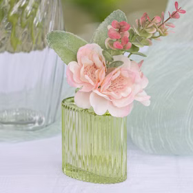 Grüne Mini-Glasvase mit rosa Kunstblüte und Blättern als frische, romantische Tischdekoration.