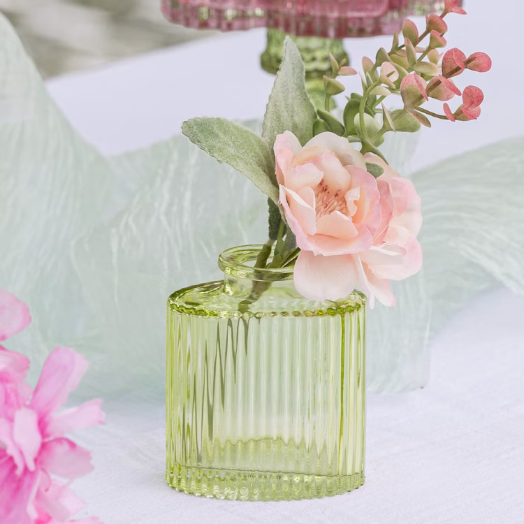 Mini Glasvasen-Set 6er Rosa Grün Klar Tisch-Deko Hochzeit Geburtstag gedeckter Tisch Blumenvase kleine Glasvase Dekoration Events Grüne Mini-Glasvase mit floraler Dekoration auf weißem Tisch und weichem Stoff im Hintergrund.