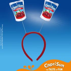 Capri Sun Cherry Haarreif Party Accessoire Roter Capri-Sun® Cherry Haarreif mit zwei wackelnden Trinkpäckchen-Motiven vor blauem Hintergrund mit Capri Sun Branding.
