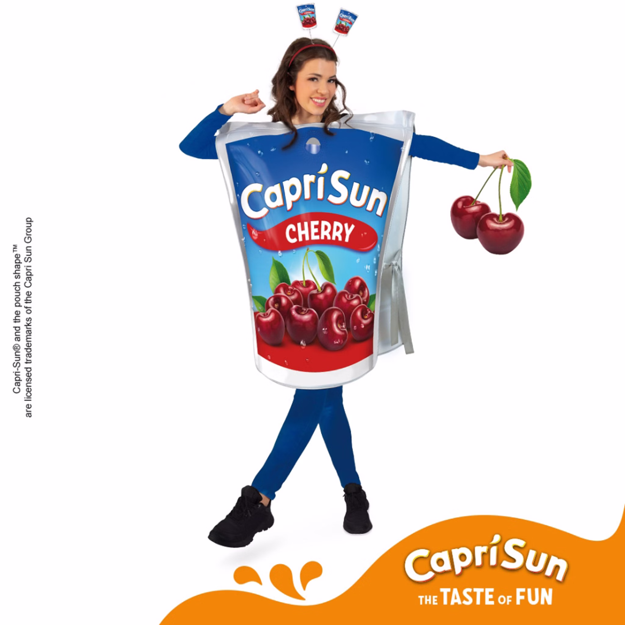 Frau im lizenzierten Capri Sun Cherry Kostüm mit Haarreif und Kirsch-Dekoration vor weißem Hintergrund mit Markenhinweis.