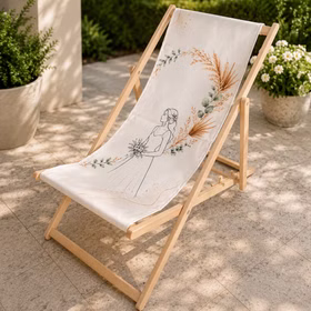 Ein Braut-Liegestuhl mit zartem Boho-Motiv steht auf heller Terrasse vor grünem Garten und weißen Blüten.