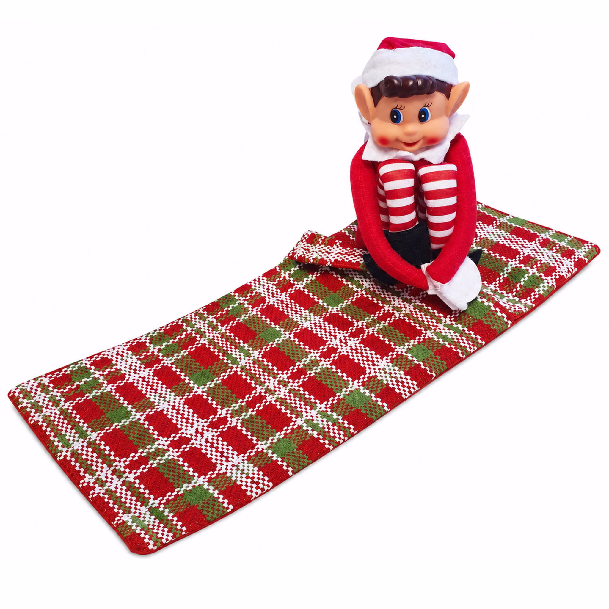 Wichtel sitzt auf ausgebreitetem Schlafsack Weihnachtswichteljunge mit roter Zipfelmütze sitzt auf dem ausgebreiteten rot grün weiß karierten Schlafsack.