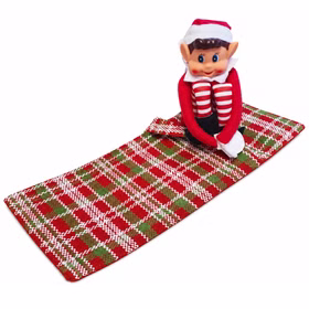 Wichtel sitzt auf ausgebreitetem Schlafsack Weihnachtswichteljunge mit roter Zipfelmütze sitzt auf dem ausgebreiteten rot grün weiß karierten Schlafsack.