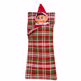 Wichtel gemütlich eingekuschelt Weihnachtswichteljunge mit roter Zipfelmütze liegt eingekuschelt im rot grün weiß karierten Schlafsack vor weißem Hintergrund.