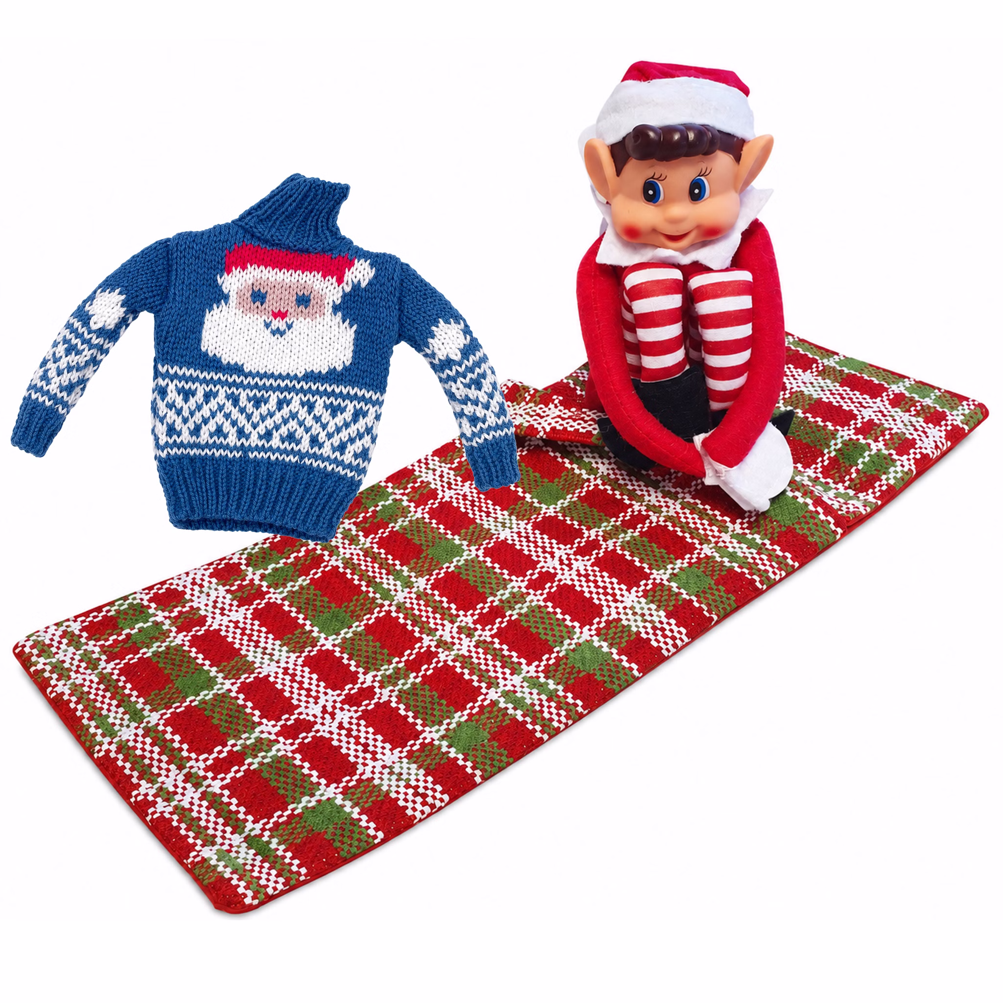 Wichteljunge mit Schlafsack und blauem Pullover Dreiteiliges Weihnachtswichtel-Set mit Wichteljunge in rotem Outfit, rot-grün-weiß kariertem Schlafsack und blauem Mini-Weihnachtspullover mit Weihnachtsmannmotiv vor weißem Hintergrund.