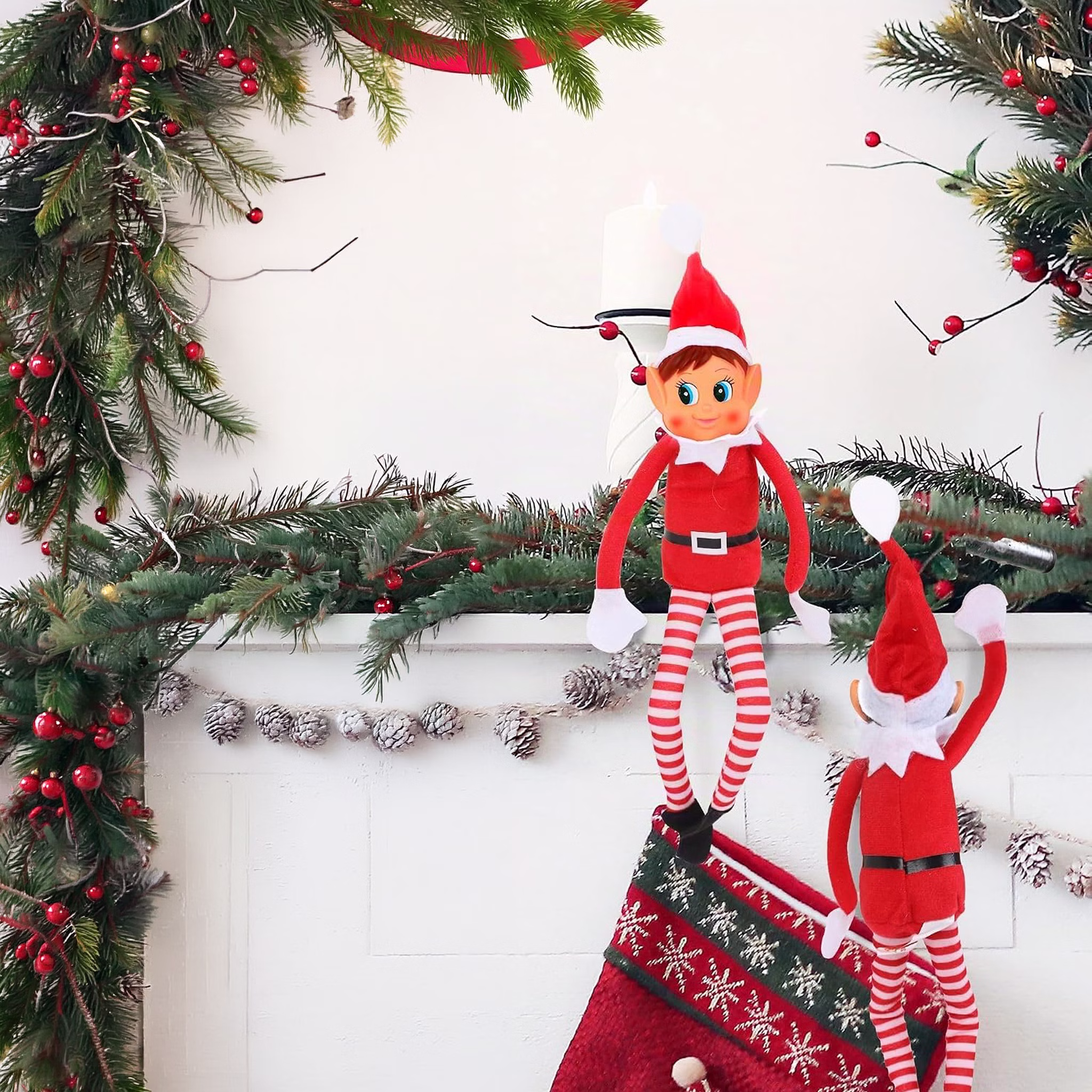 Wichtel in weihnachtlicher Dekoration Zwei Weihnachtswichtel von Elf with Big Ears dekorieren einen weihnachtlichen Bereich mit Tannenzweigen und einem einer Socke mit Norwegermuster.