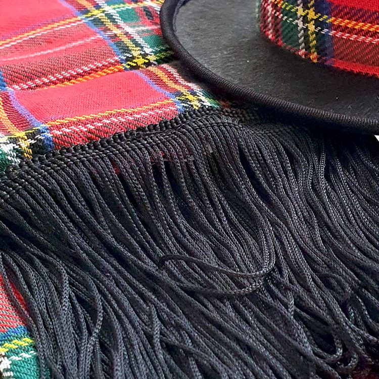 Rot-Grün karierter Schal mit schwarzen Fransen und daneben ein schwarzer Mini-Zylinder mit passender karierter Hutkrone von Vorn